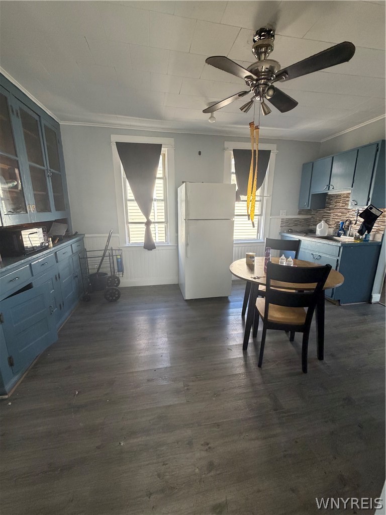 Kitchen with blue cabinets, a central white refrigerator, and a round dining table.