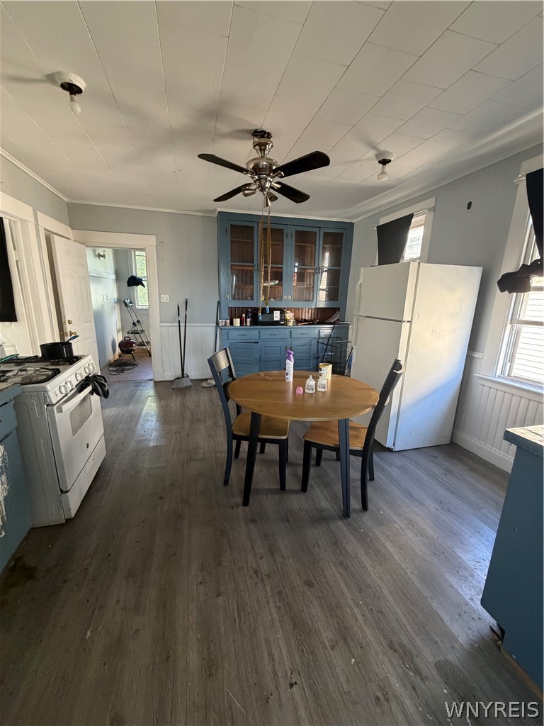 Kitchen with blue cabinets, white appliances, and a round table and chairs.