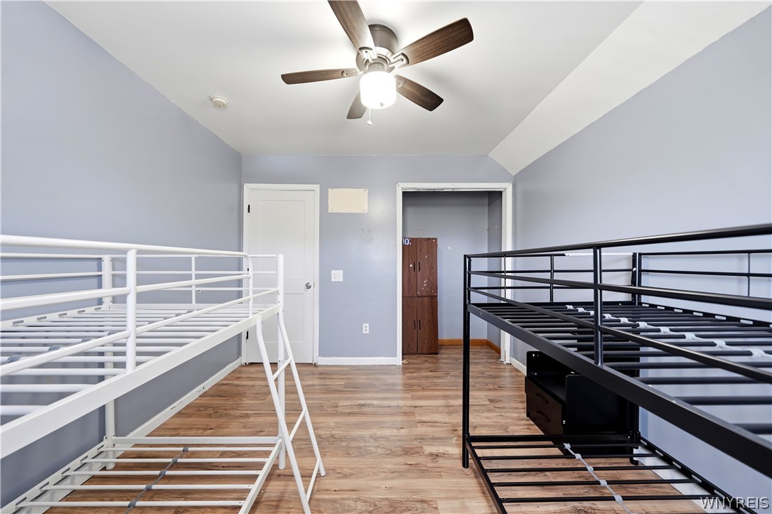 Bedroom with white and black metal bed frames, wood-look flooring, and a ceiling fan.