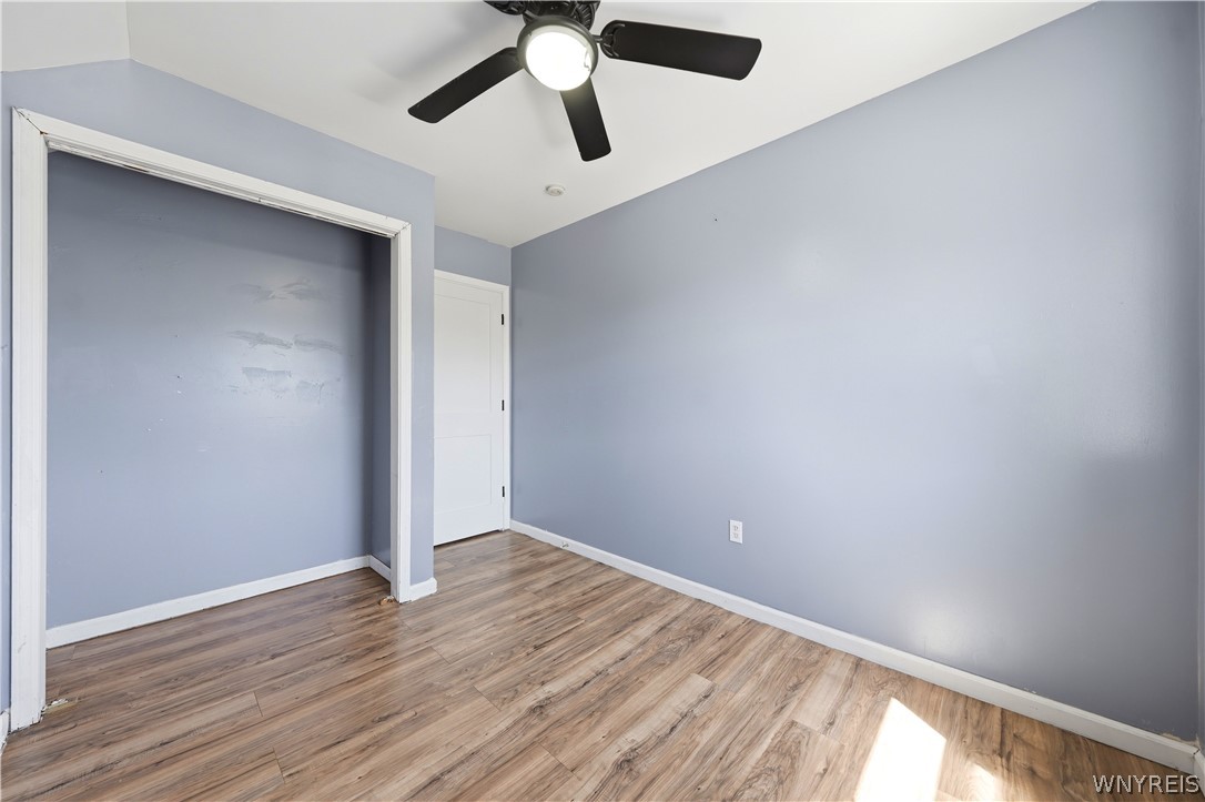 Empty blue room with wood-look flooring and a ceiling fan.