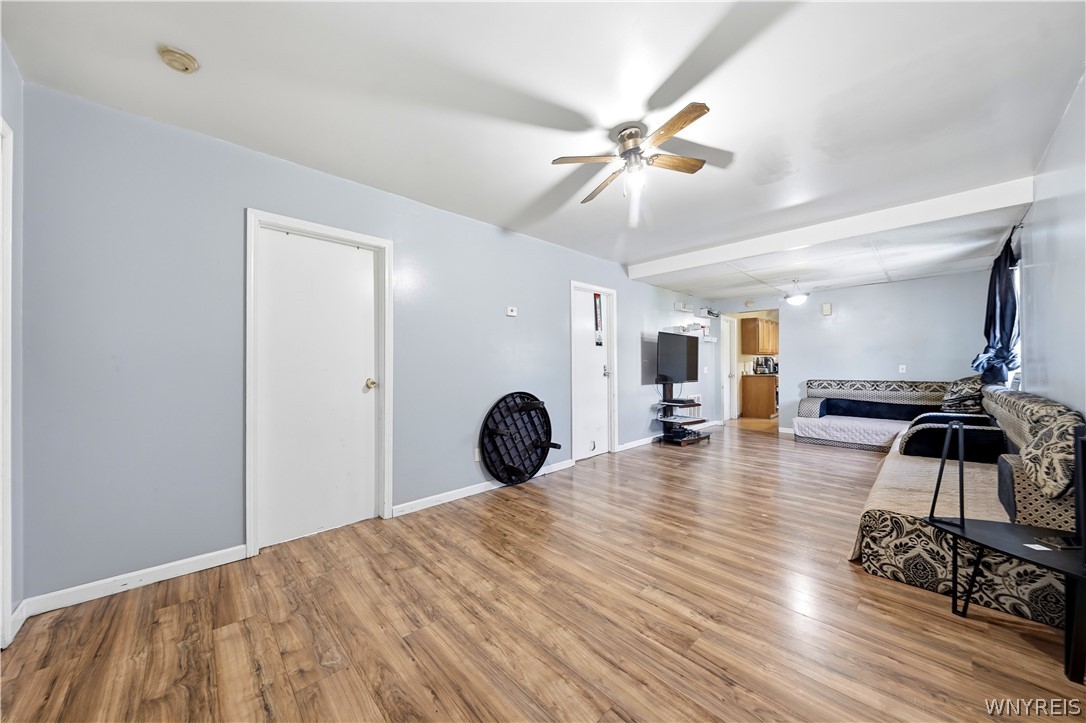 Living room with wood-look flooring, a ceiling fan, and patterned sofas.