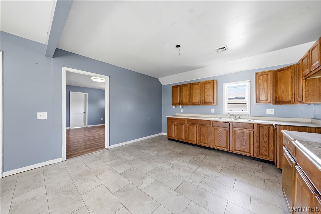 Kitchen with wood cabinets, gray walls, and a large tiled floor.