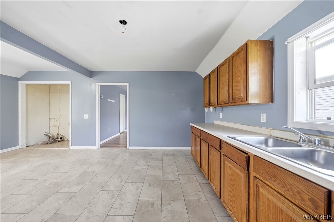 Kitchen with blue-gray walls, wood cabinets, tile flooring, and a double-basin sink.