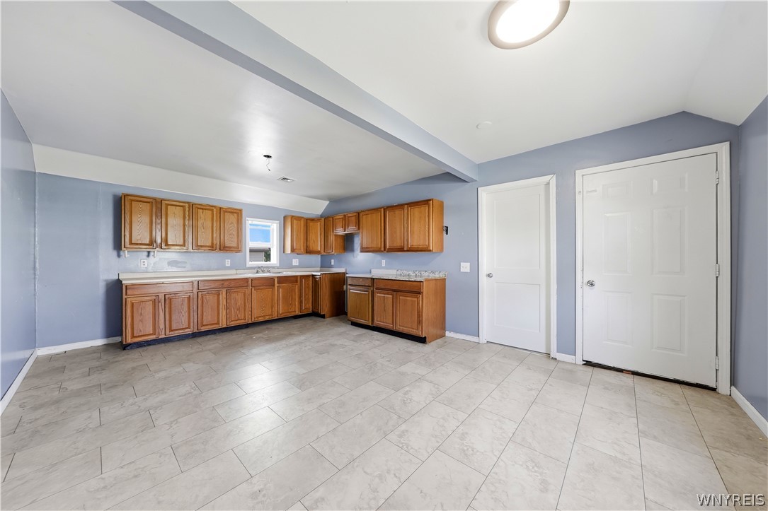 Vacant kitchen with wood cabinets, blue walls, and light tile flooring.