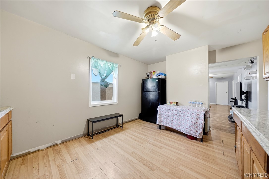Kitchen and dining area with light wood floors, a black refrigerator, and a table by an open doorway.
