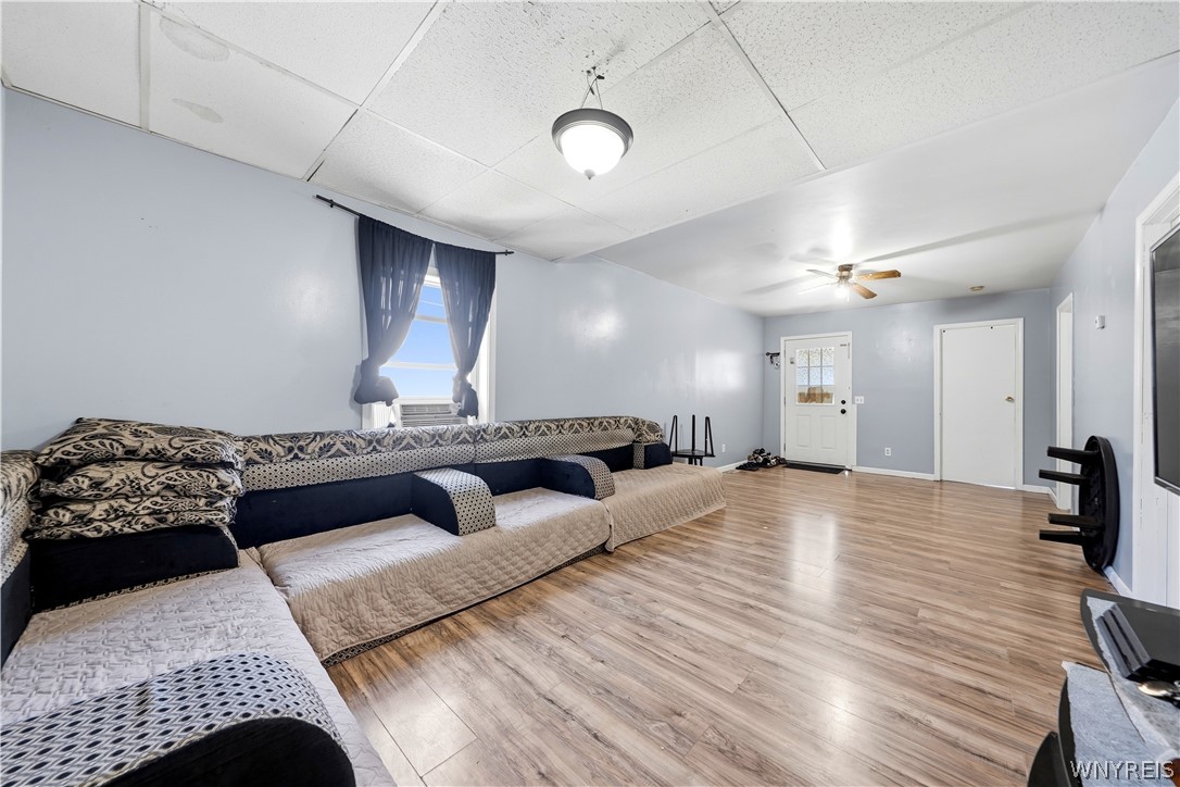 Living room with a large patterned sectional sofa and wood-look flooring.