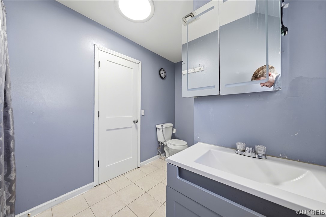 Bathroom with a white bathtub, blue vanity, toilet, and mirrored medicine cabinets.