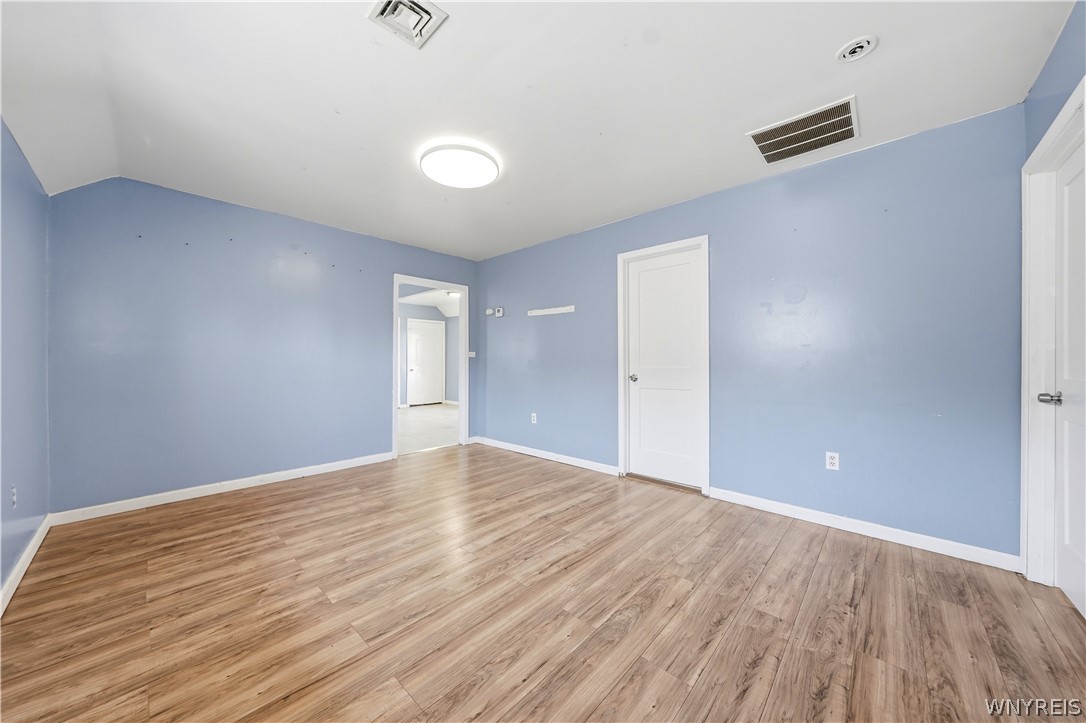 Empty blue room with wood-look plank flooring and a doorway opening to the hall.