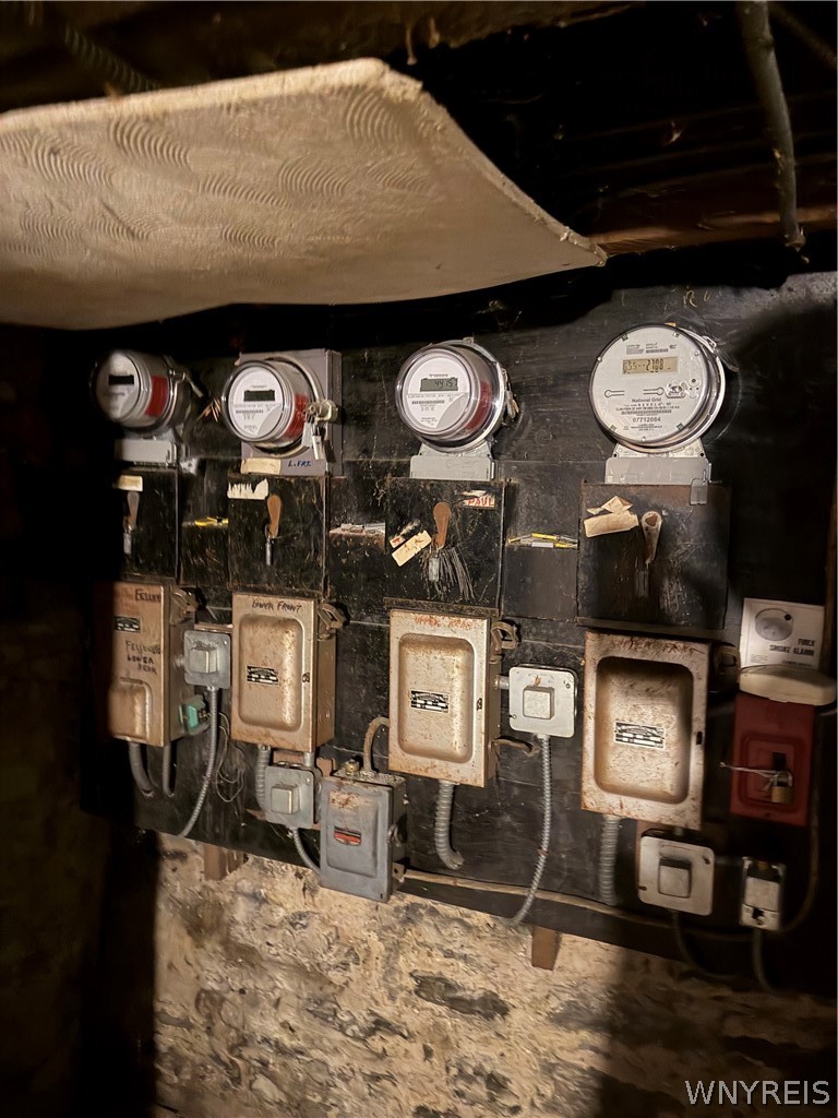 Basement electrical meters and service panels against exposed stone foundation walls.