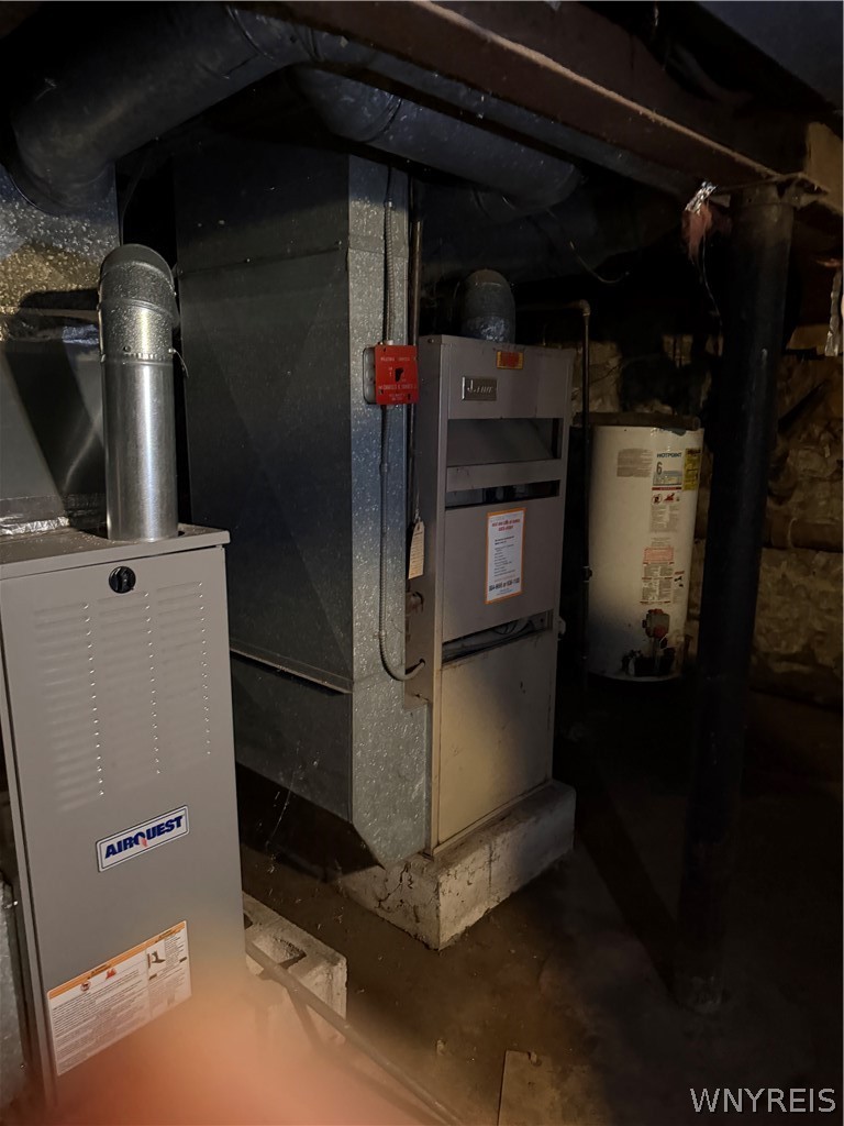 Basement mechanical area with two furnaces, a hot water tank, and exposed ductwork.