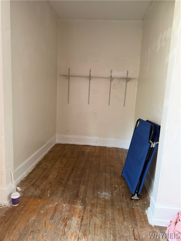 Narrow closet with wire shelving and worn wood flooring.