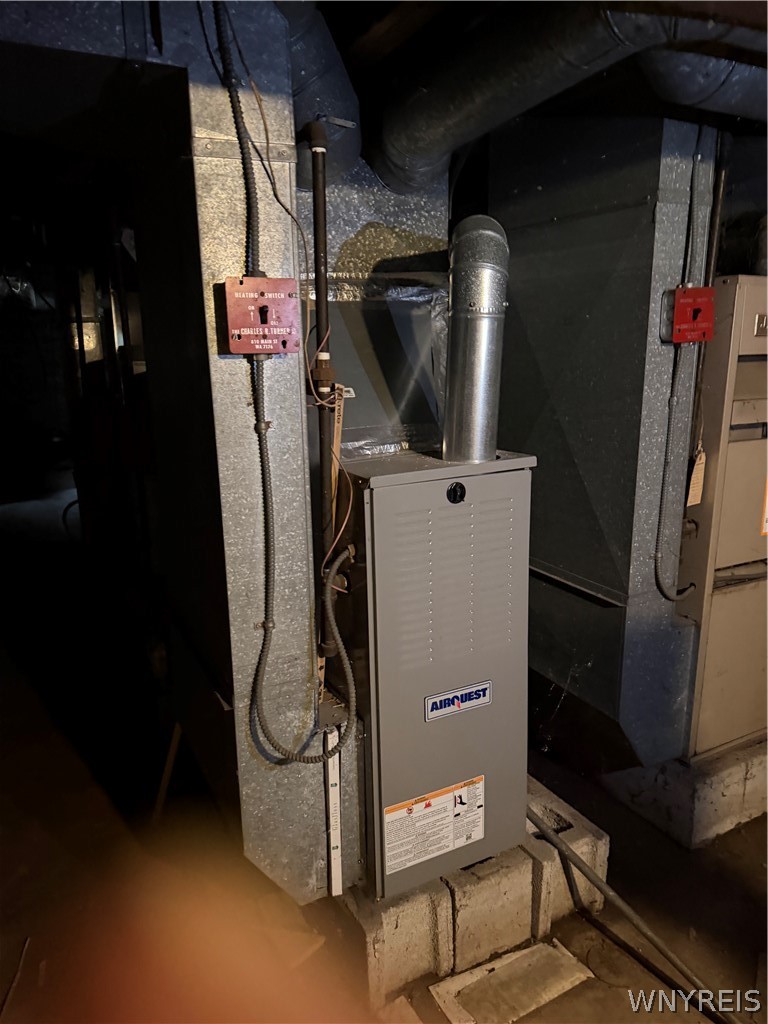 Basement furnace with metal ductwork and exposed utility lines.