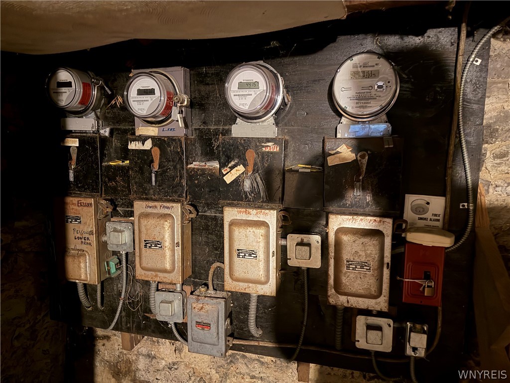 Basement electrical panels and meters mounted along a dark utility wall.