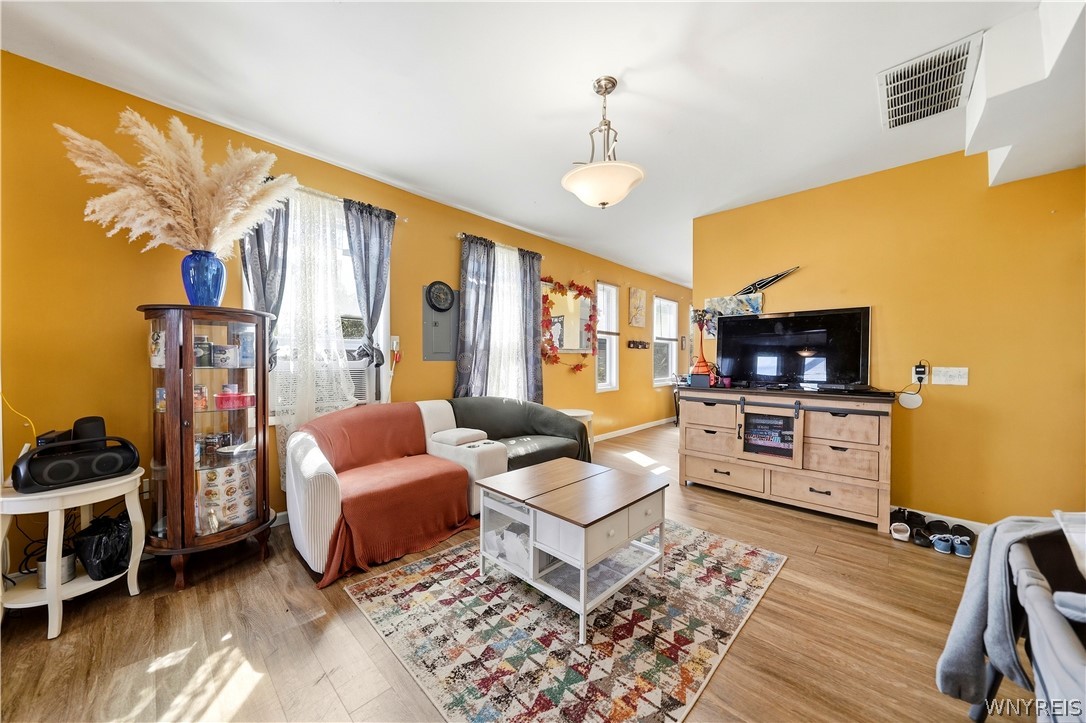 Living room with mustard-orange walls, a sectional sofa, and a patterned area rug.