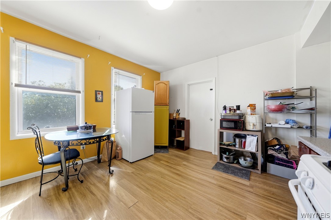 Kitchen with a yellow accent wall, white refrigerator, and glass-topped dining table.