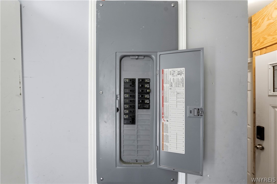 Open electrical breaker panel with rows of circuit breakers and a directory inside the door.