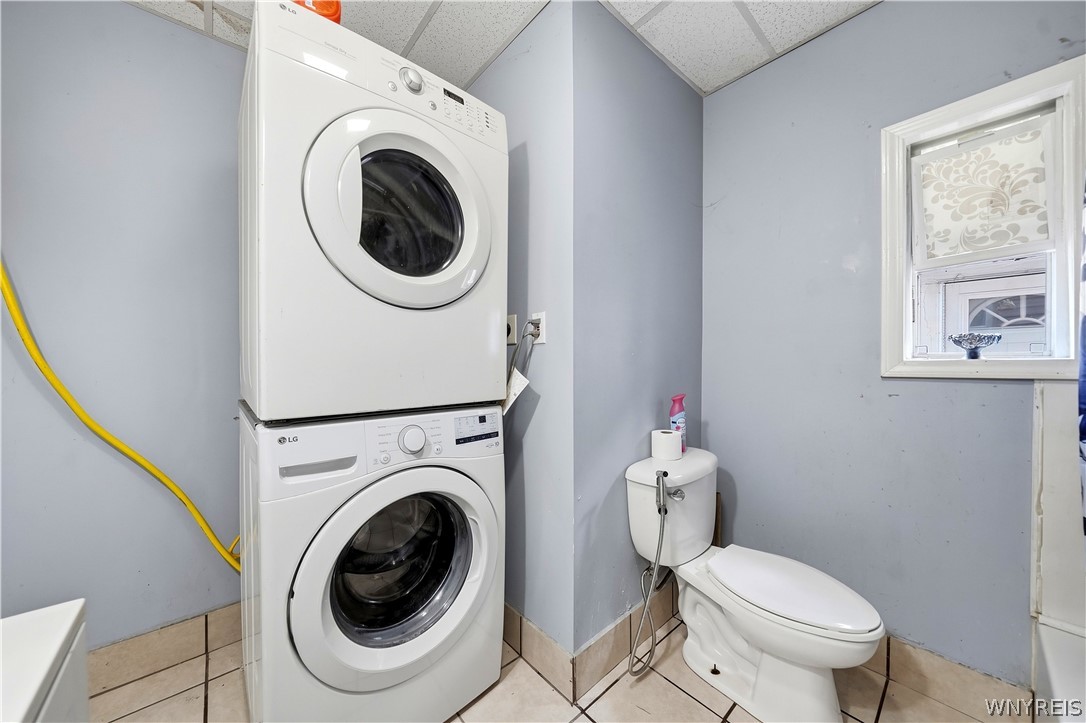 Bathroom with a stacked front-load washer and dryer beside a toilet.