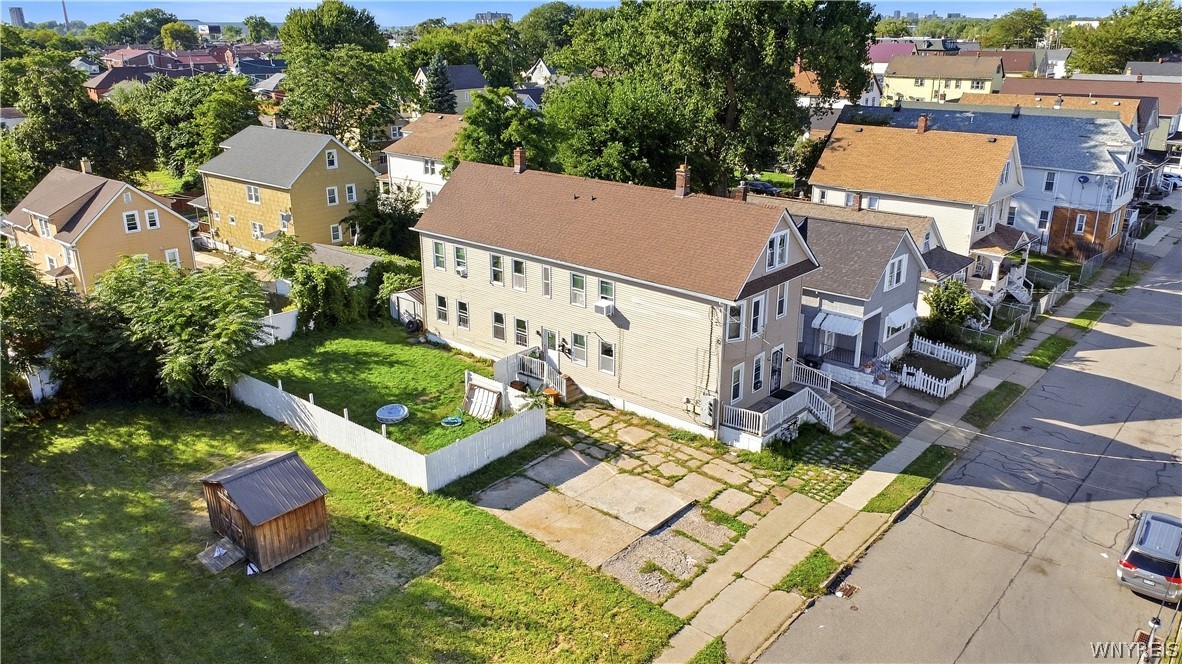 Aerial view of a beige multi-unit home with a fenced backyard and shed.