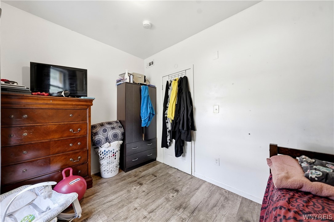 Bedroom with a wooden dresser, television, wardrobe, and bed along the right edge.