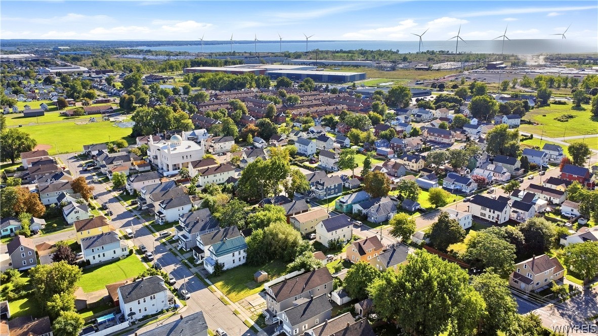 Aerial view of a residential neighborhood, with distant water and wind turbines on the horizon.