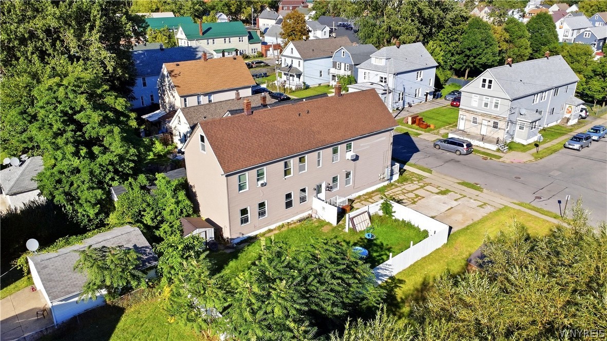 Aerial view of a tan two-story home with a fenced backyard and mature trees.