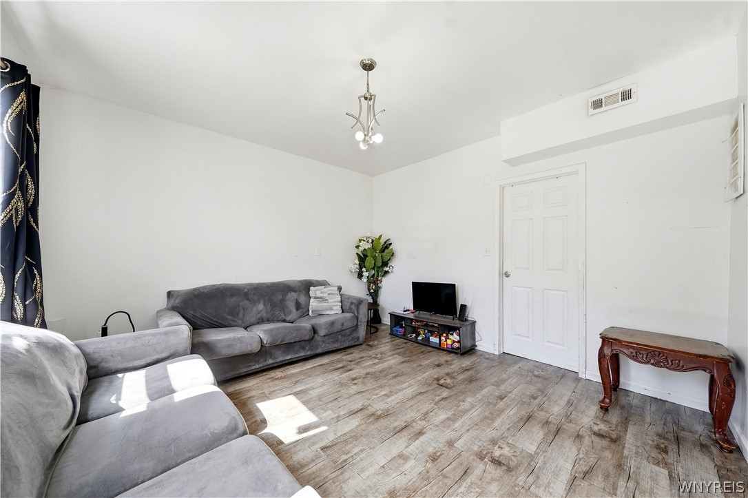 Furnished living room with gray sectional sofas, wood-look flooring, and a small television.