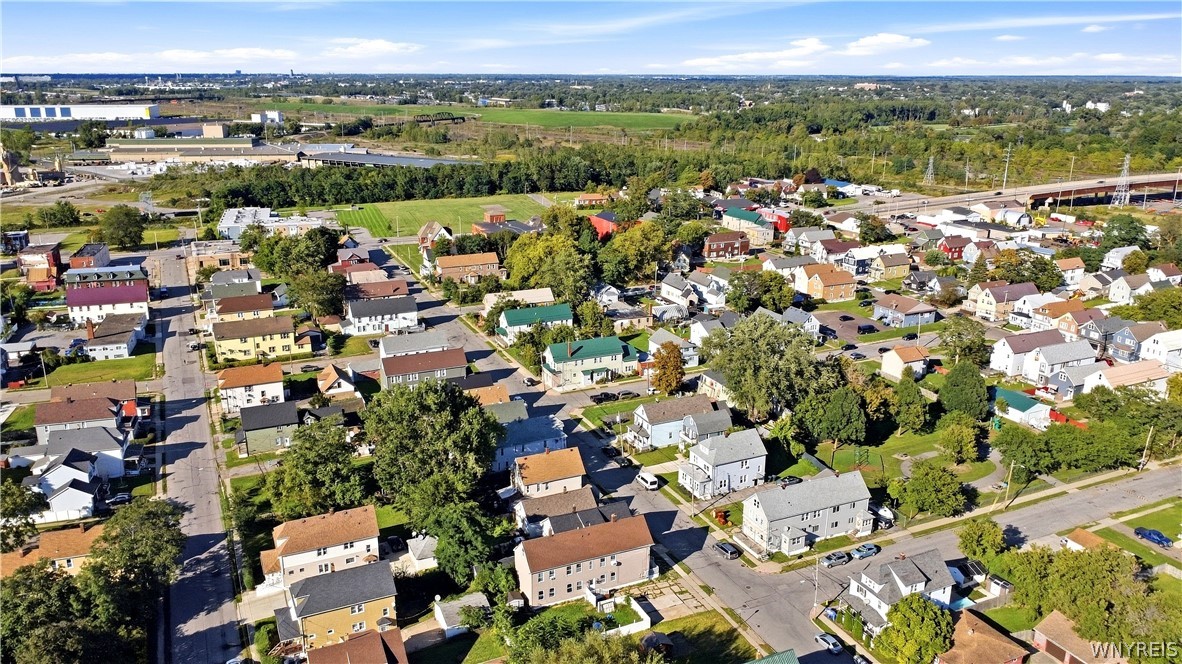 Aerial view of a residential neighborhood with tree-lined streets and a highway in the distance.