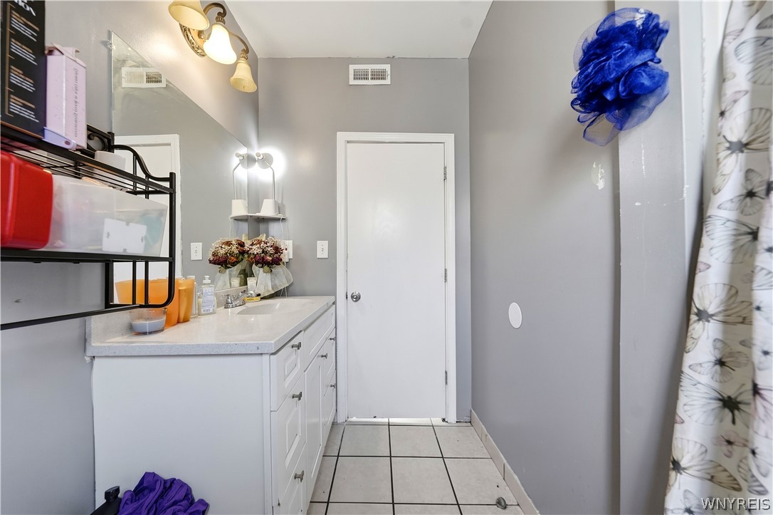 Bathroom with a white vanity, tiled floor, and floral shower curtain.