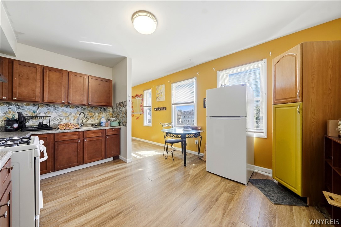 Kitchen with dark wood cabinets, mustard-yellow walls, and a small dining table by the windows.