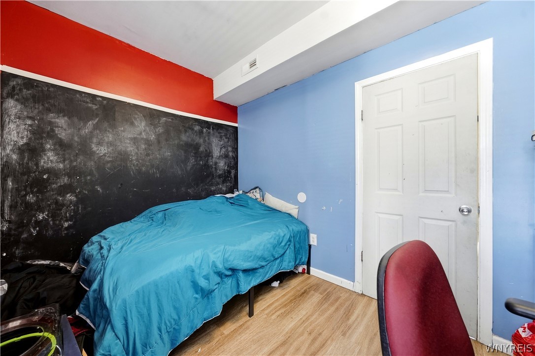 Bedroom with a blue-covered bed, black chalkboard wall, and red chair.