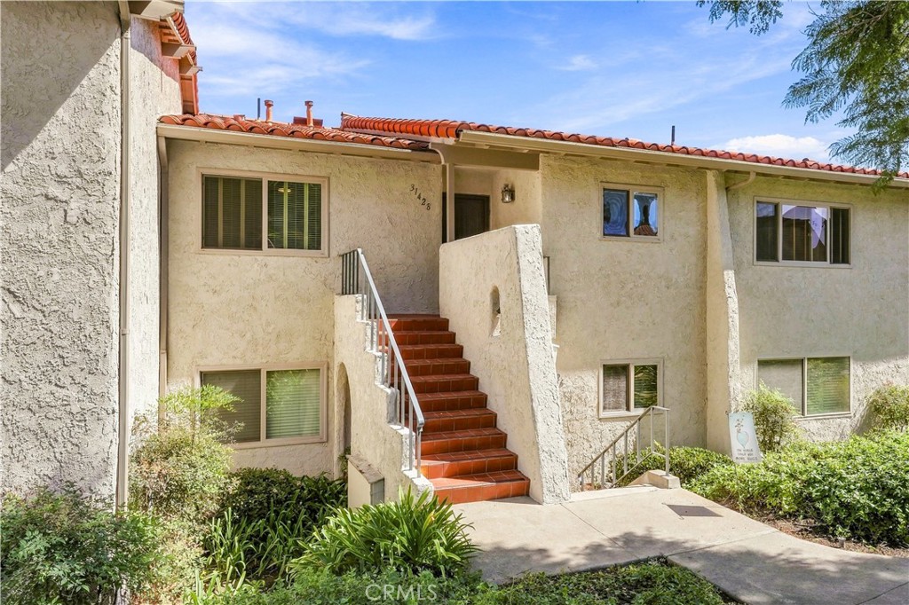 Two-story stucco residence with a terracotta tile roof and red-tiled entry stairs.