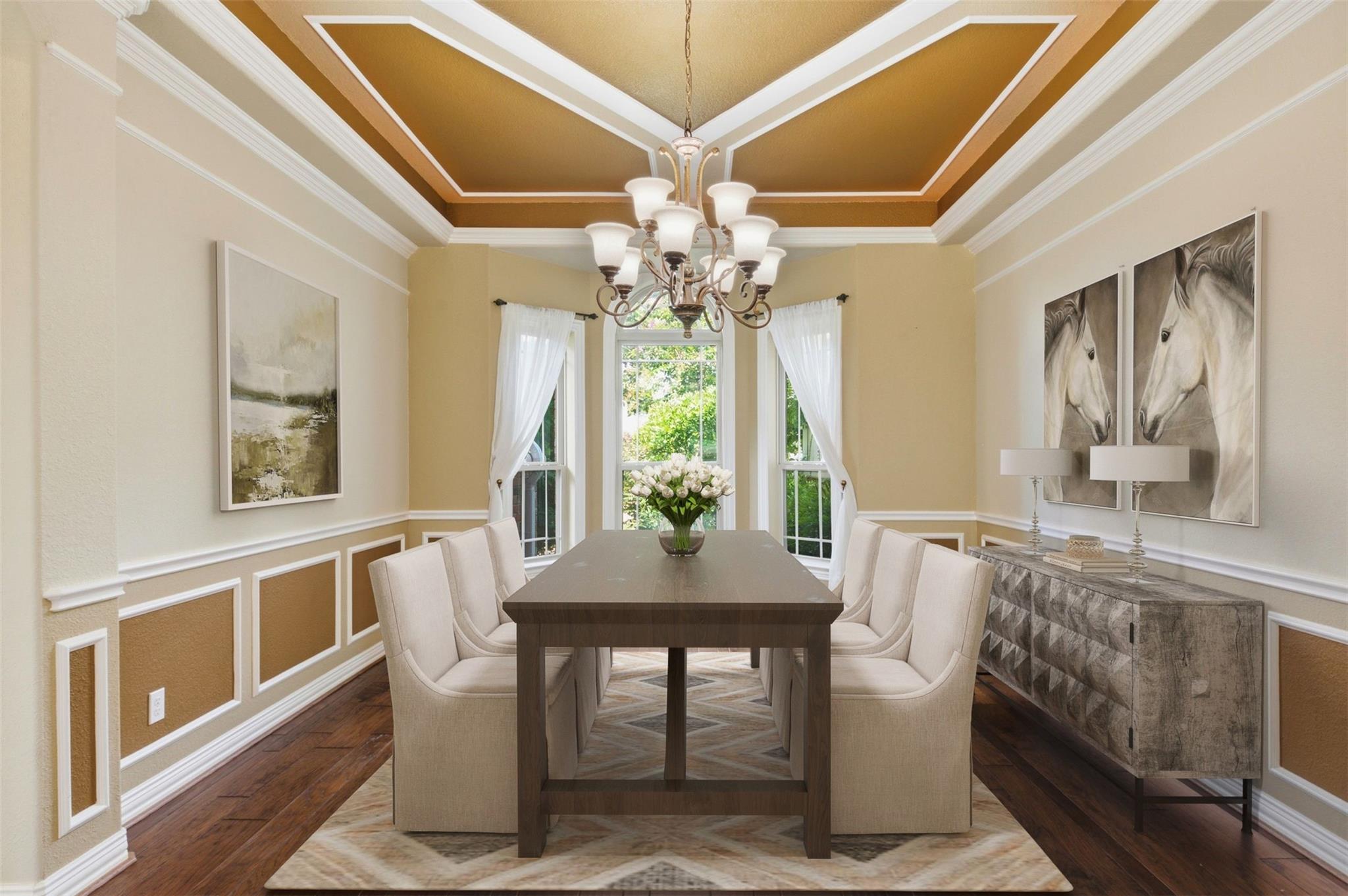 Dining room with a tray ceiling, chandelier, dark wood table, and tall curtained windows.