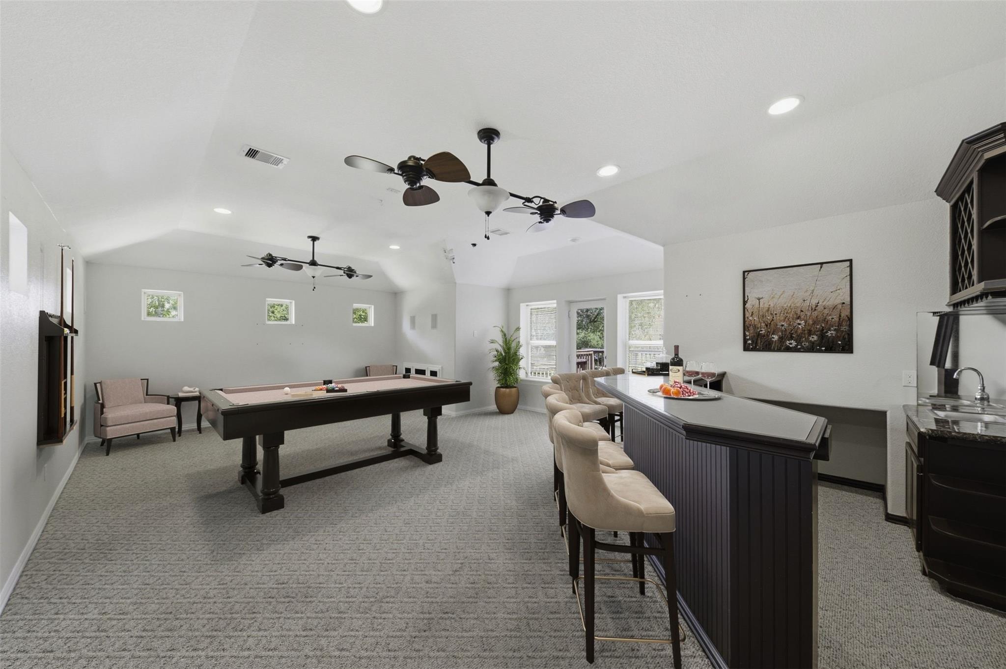 Game room with a billiards table and a long bar lined with upholstered stools.