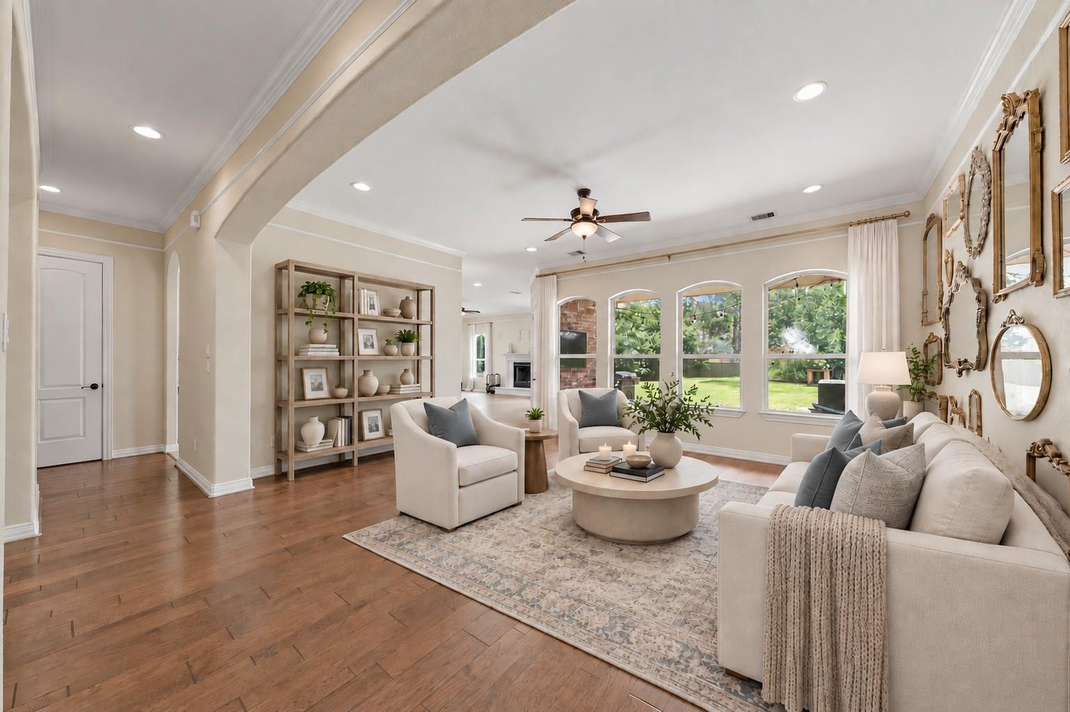 Staged living room with cream seating, arched windows, built-in shelves, and a patterned rug.