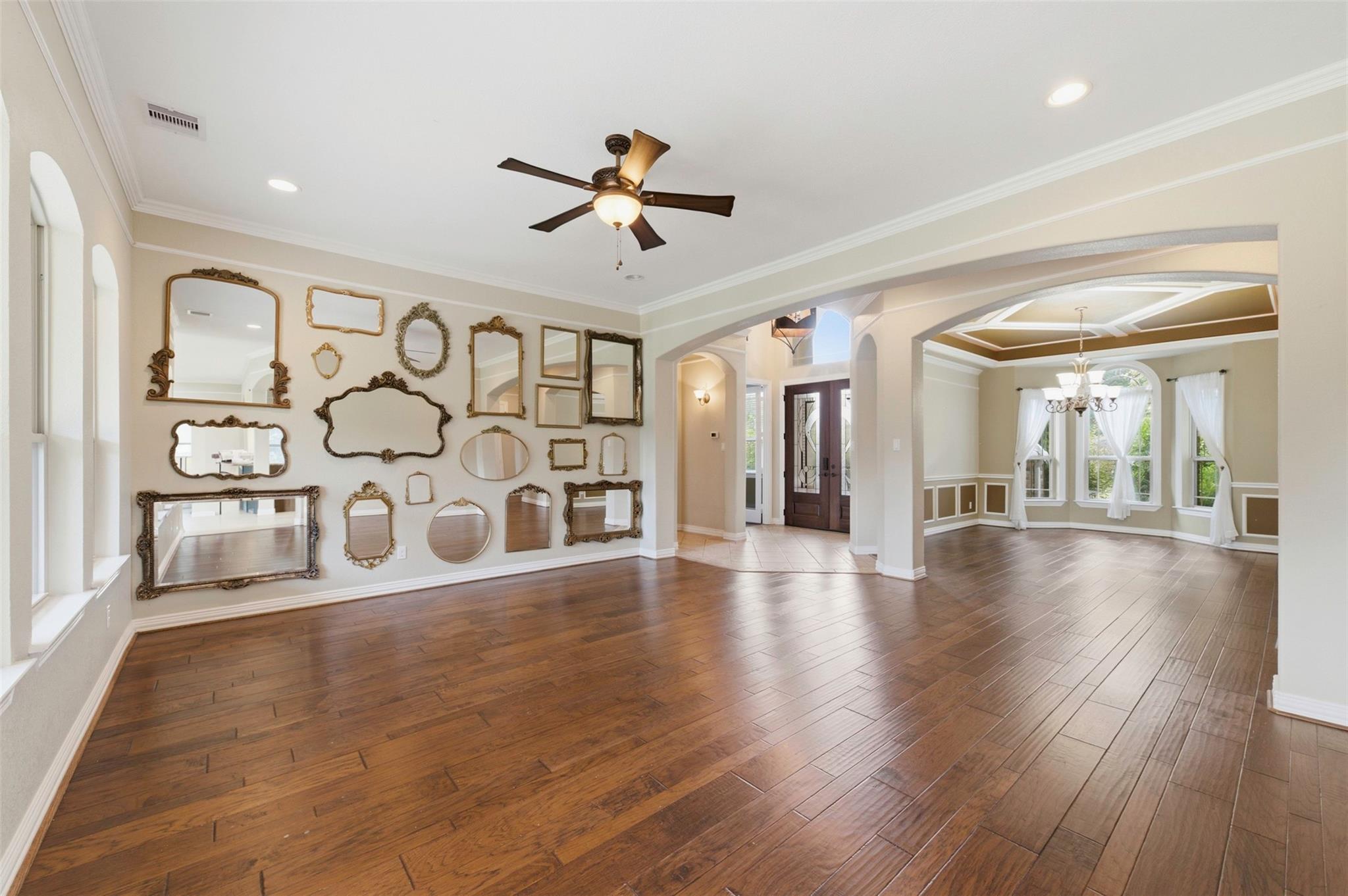 Open wood-floored interior with a wall of decorative mirrors and an adjoining dining area with large windows.