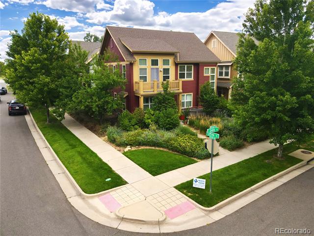 Two-story red-and-yellow home on a landscaped corner lot beneath mature trees.