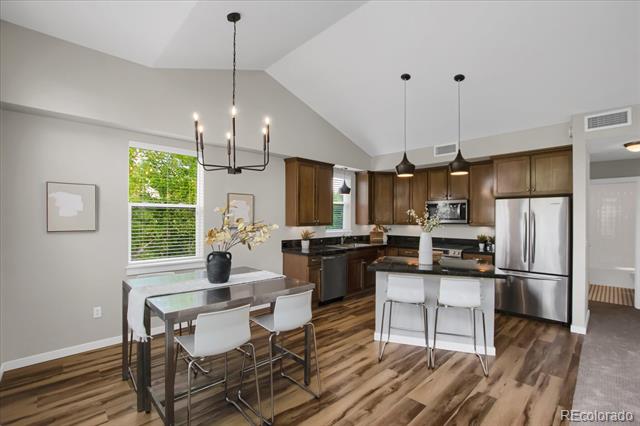 Open-plan kitchen with a large island, dark wood cabinets, stainless steel appliances, and an adjacent dining area.
