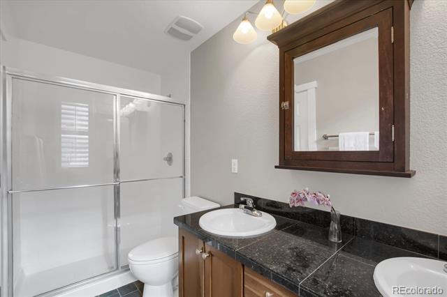 Bathroom with a glass-enclosed shower and dark granite vanity beneath a wood-framed mirror.