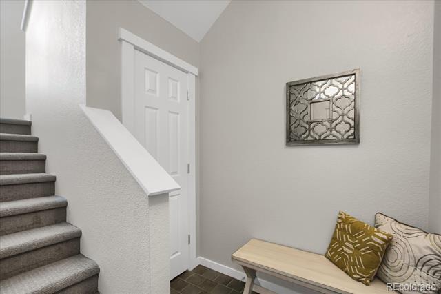 Entry hall with carpeted stairs and a light wood bench with patterned pillows.