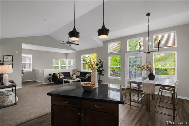 Open-plan kitchen and living area with a dark island, dining table, and large windows.