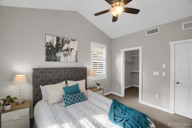 Staged bedroom with a gray tufted headboard, teal accents, and an open closet.