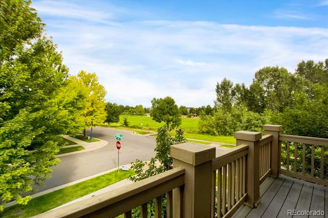 Wooden deck overlooking a tree-lined street and green park.