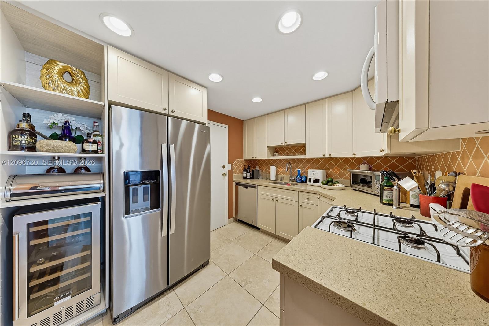 Kitchen with cream cabinets, stainless-steel appliances, a tiled backsplash, and a gas cooktop.