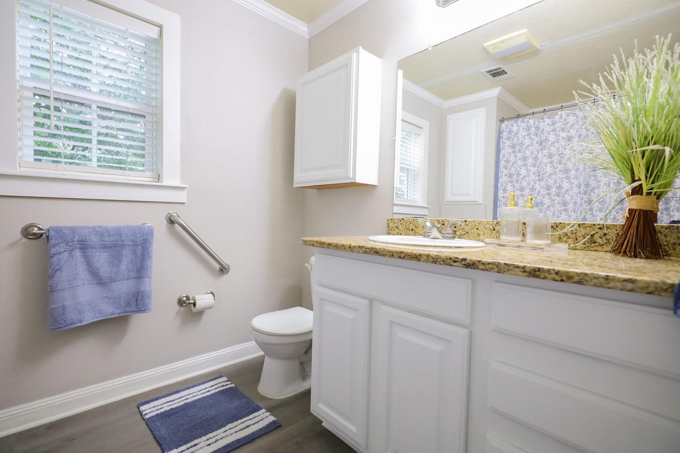 Bathroom with a granite-topped white vanity, toilet, and blue patterned shower curtain.