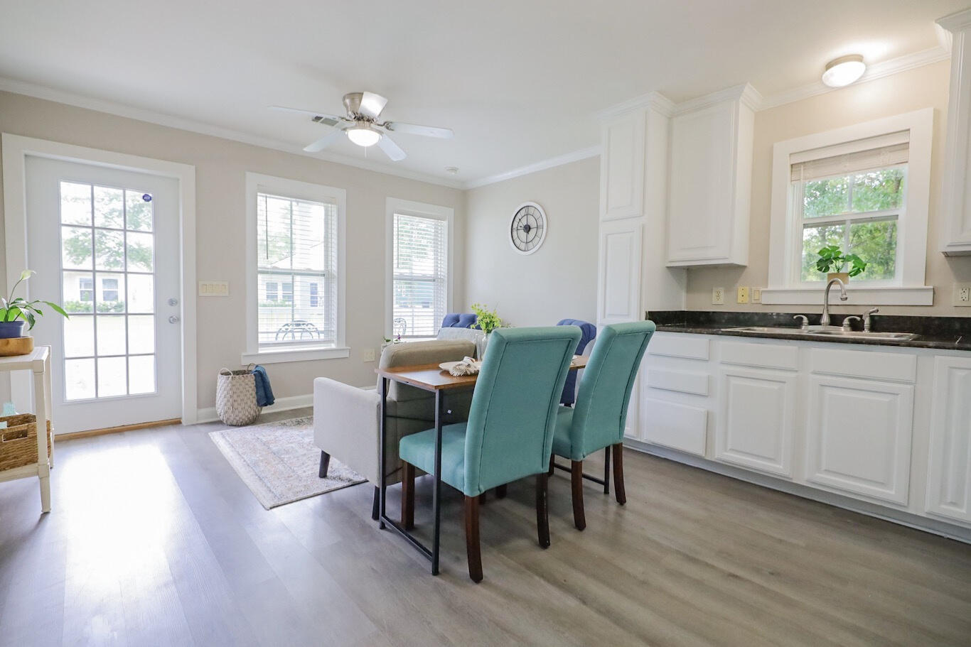 Kitchen and dining area with white cabinets, dark countertops, and teal dining chairs.