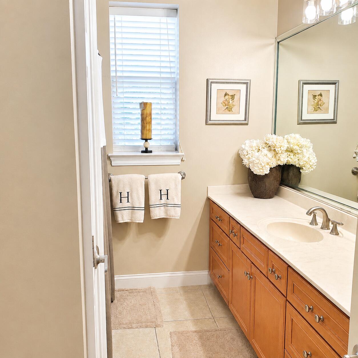 Bathroom with a wood vanity, oval sink, large mirror, and window with white blinds.