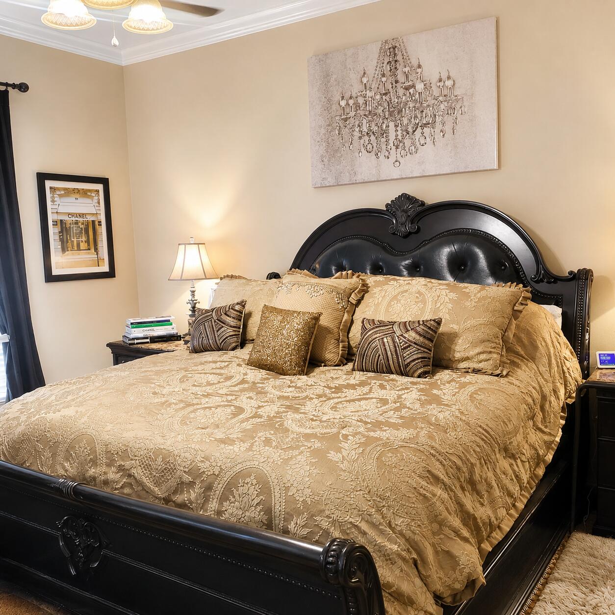 Furnished bedroom with an ornate black bed and gold patterned bedding.