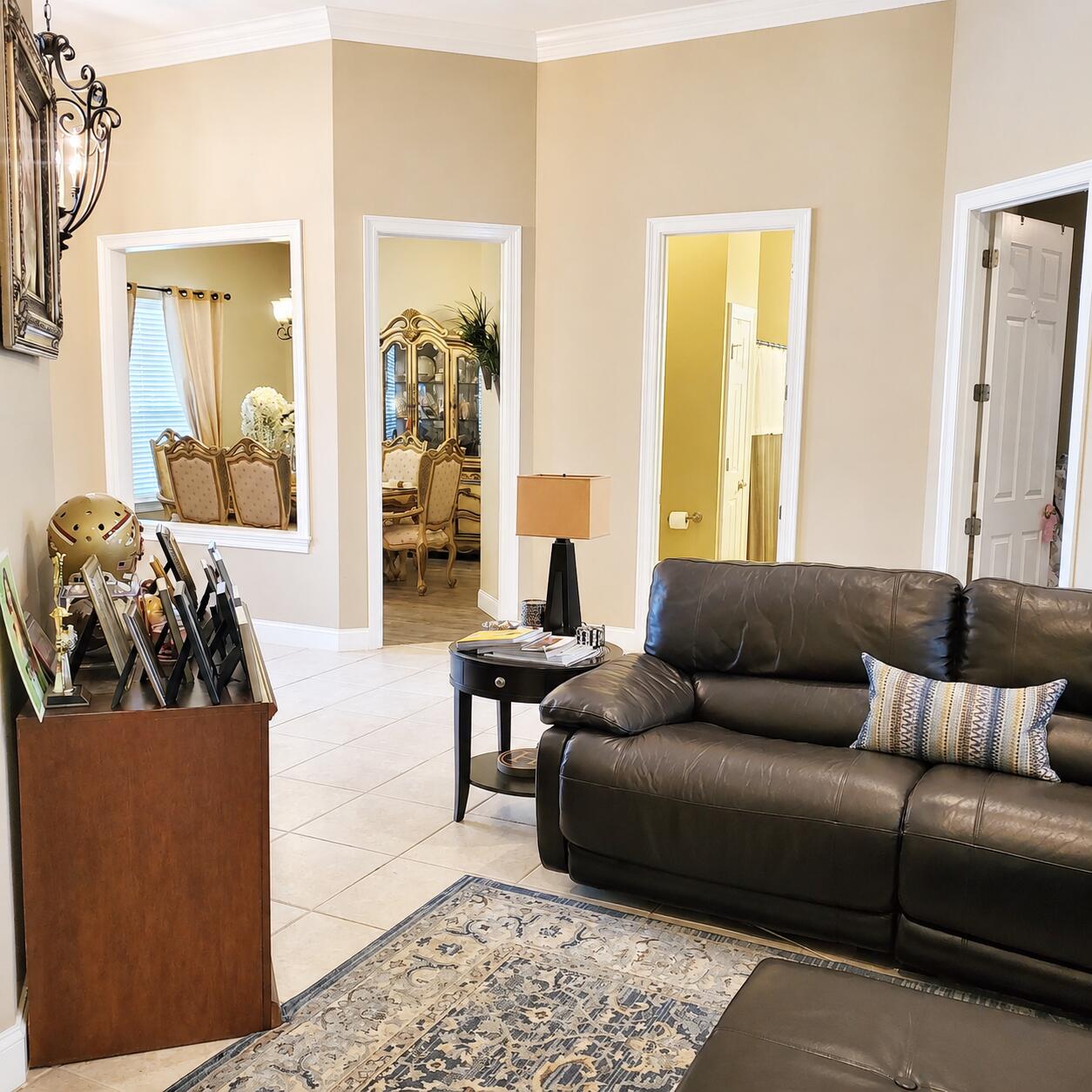 Living room with a dark leather sofa, patterned rug, and open doorways to adjoining rooms.