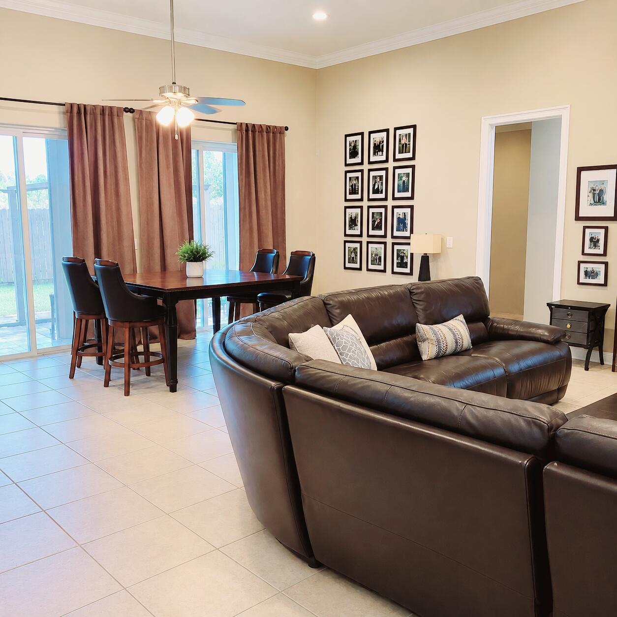 Living and dining area with a leather sectional, dining table, and sliding glass doors to a patio.
