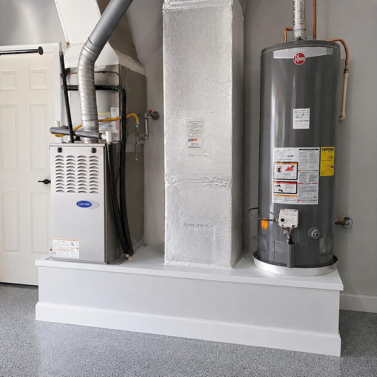 Utility room with a Carrier furnace and Rheem water heater on a raised platform.